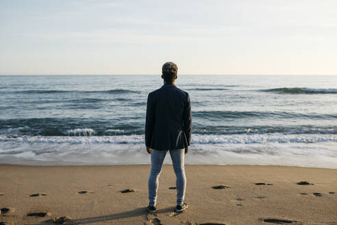 Mann schaut am Strand stehend auf die Aussicht - JRFF05042