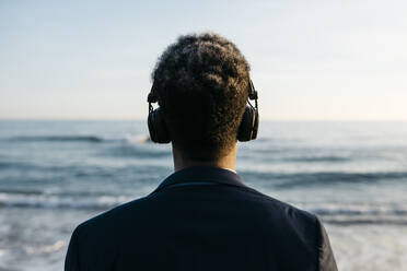 Afro-Mann mit Kopfhörern am Strand - JRFF05043