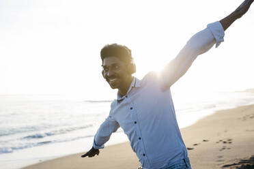 Smiling man enjoying at beach while imitating airplane - JRFF05056