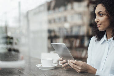 Junge Geschäftsfrau, die ein digitales Tablet benutzt, während sie in einem Café sitzt - JOSEF03438