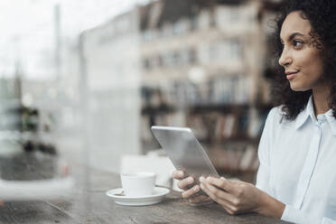 Young businesswoman using digital tablet while sitting at cafe - JOSEF03438