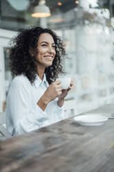 Lächelnde Geschäftsfrau, die in einem Café sitzt und Kaffee trinkt - JOSEF03458