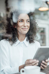 Businesswoman with digital tablet smiling while sitting at cafe - JOSEF03460