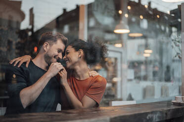 Paar sitzt lächelnd mit Arm um einander im Café - JOSEF03481