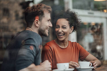 Happy couple having coffee while sitting at cafe - JOSEF03507