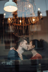 Freund und Freundin küssen sich, während sie im Café sitzen - JOSEF03516
