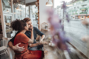 Freundin schaut ihren Freund an, während sie im Café sitzt - JOSEF03518