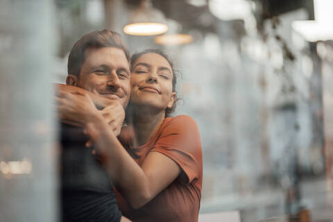 Young woman embracing man while sitting at cafe stock photo