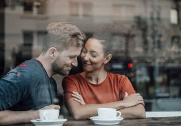 Couple smiling while sitting by cafe window - JOSEF03561