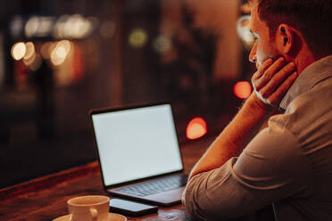 Geschäftsmann arbeitet am Laptop, während er im Café sitzt - JOSEF03595