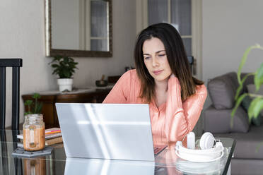 Beautiful businesswoman using laptop while sitting at dining table in home office - AFVF08169
