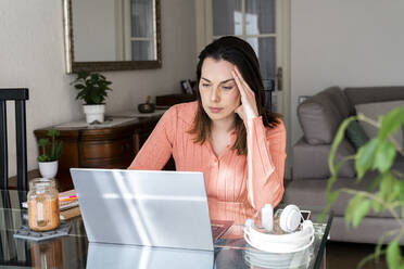 Besorgte Unternehmerin arbeitet zu Hause am Laptop - AFVF08171