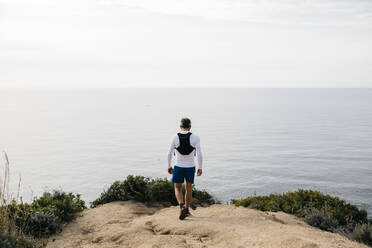 Man walking at cliff near sea against clear sky - JRFF05065