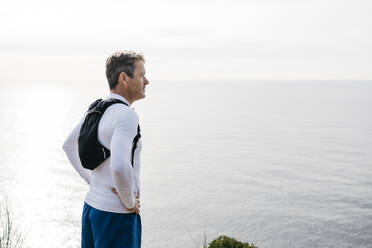 Man standing with hand on hip near sea against clear sky - JRFF05068