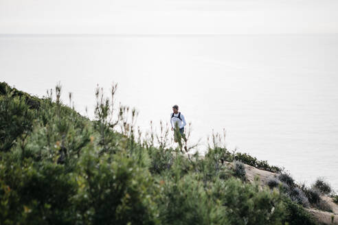 Mann läuft auf einen Berg am Meer - JRFF05077