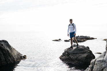 Mature man standing on rock amidst sea against clear sky - JRFF05078