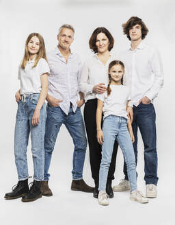 Glückliche Familie mit Kindern, die vor einem weißen Hintergrund stehen - DHEF00565