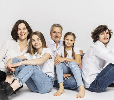 Familie mit Kindern sitzend vor weißem Hintergrund - DHEF00580