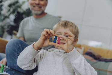 Boy holding toy figurines in living room - MFF07155