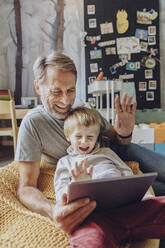 Happy father and son video calling through digital tablet - MFF07170