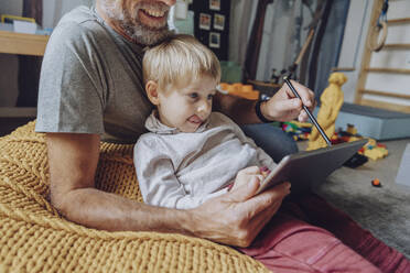 Vater hilft seinem Sohn beim E-Learning auf dem Tablet zu Hause - MFF07171