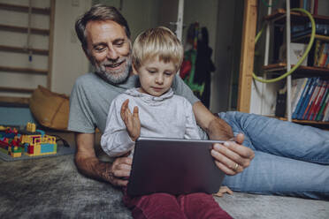 Glücklicher Vater und Sohn führen zu Hause Videogespräche über ein digitales Tablet - MFF07185