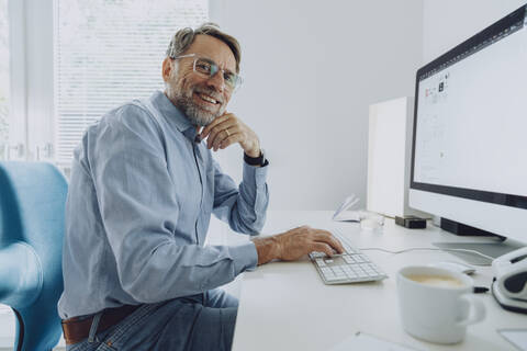 Smiling mature businessman working at home office stock photo