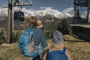 Mann mit zwei Kindern, der die Seilbahn auf dem Hochkonig im Salzburger Land, Österreich, betrachtet - MFF07213