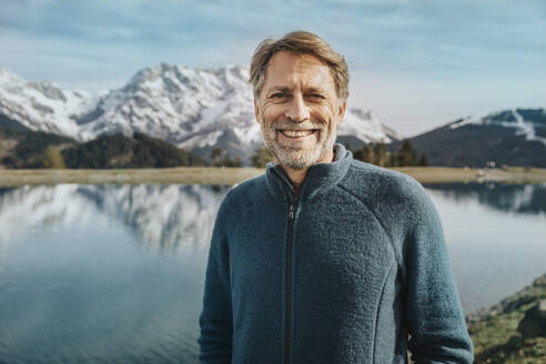 Smiling mature man standing against lake at Salzburger Land, Austria - MFF07218