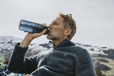 Mature man drinking water against sky at Salzburger Land, Austria - MFF07224
