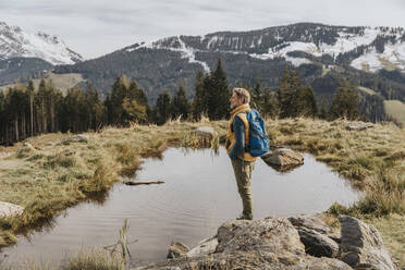 Mature man standing on rock by pond while looking away at Salzburger Land, Austria - MFF07225