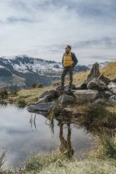 Älterer Mann auf einem Felsen an einem Teich im Salzburger Land, Leoganger Berge, Österreich - MFF07232