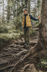 Man standing on roots of tree in forest at Salzburger Land, Austria - MFF07240