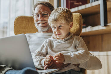 Lächelnder Vater mit Sohn beim E-Learning am Laptop - MFF07262