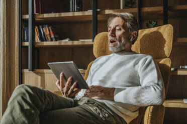 Mann, der zu Hause sitzend eine Videokonferenz über ein digitales Tablet führt - MFF07274