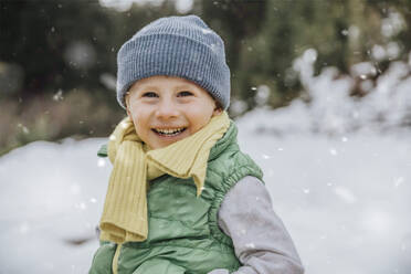 Lächelnder süßer Junge auf schneebedecktem Land während des Winters - MFF07297