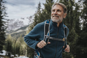 Lächelnder reifer Mann, der beim Wandern im Wald im Salzburger Land, Österreich, wegschaut - MFF07308