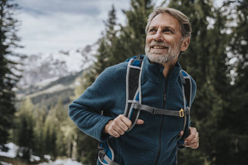 Smiling mature man looking away while hiking in forest at Salzburger Land, Austria - MFF07308