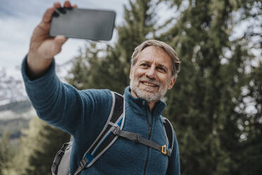 Smiling mature man taking selfie through mobile phone against tree at Salzburger Land, Austria - MFF07310
