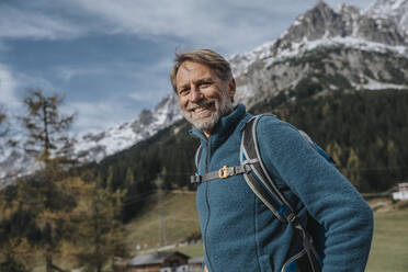 Lächelnder reifer Mann mit Rucksack vor dem Himmel am Hochkonig, Salzburger Land, Österreich - MFF07316