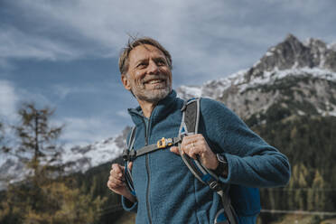 Lächelnder reifer Mann mit Rucksack und Blick in den Himmel am Hochkonig, Salzburger Land, Österreich - MFF07317