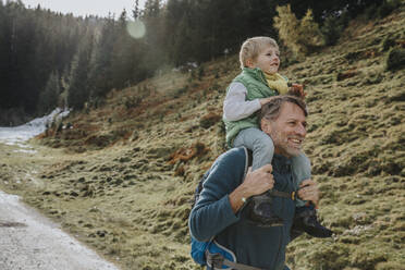 Vater trägt Sohn auf der Schulter bei einem Waldspaziergang im Salzburger Land, Österreich - MFF07319