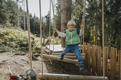 Junge im Hochseilgarten im Wald im Salzburger Land, Österreich - MFF07333