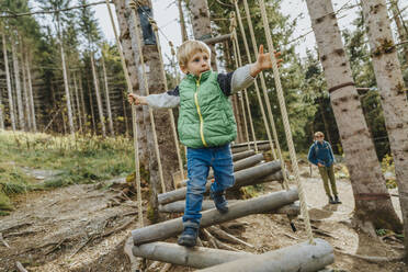 Boy looking away while doing rope course in forest at Salzburger Land, Austria - MFF07335