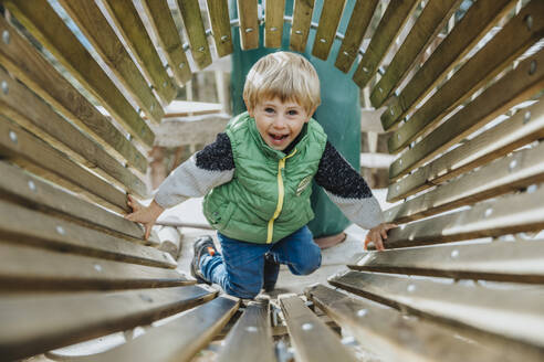 Verspielter Junge in einem Holztunnel im Wald im Salzburger Land, Österreich - MFF07336