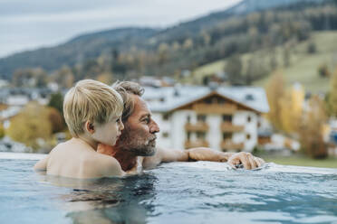 Vater und Sohn im Infinity-Pool mit Blick in das Salzburger Land, Österreich - MFF07342