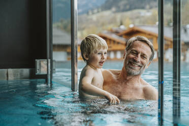 Lächelnder Vater mit Sohn im Infinity-Pool eines Hotels - MFF07346