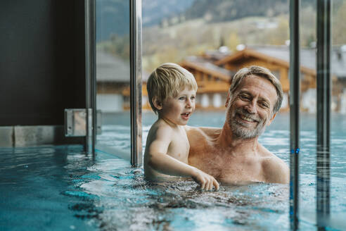 Smiling father with son enjoying in infinity pool at hotel - MFF07346