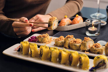 Junger Kunde isst Sushi mit Stäbchen im Restaurant - AODF00304