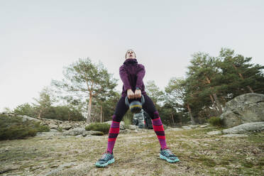 Woman exercising with kettlebell at forest - MRRF00901